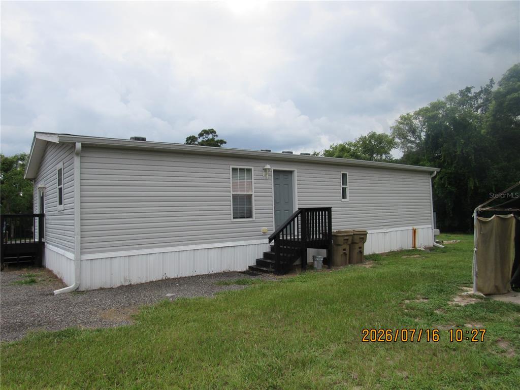 A light gray manufactured home with white skirting and a small black wooden staircase — 11719 LAKE DRIVE, CLERMONT, FL