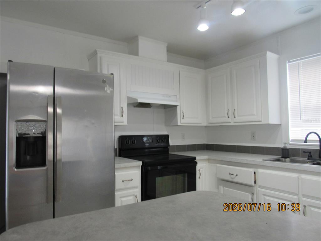 A kitchen features white cabinets, stainless steel appliances, a black stove, and gray countertops — 11719 LAKE DRIVE, CLERMONT, FL