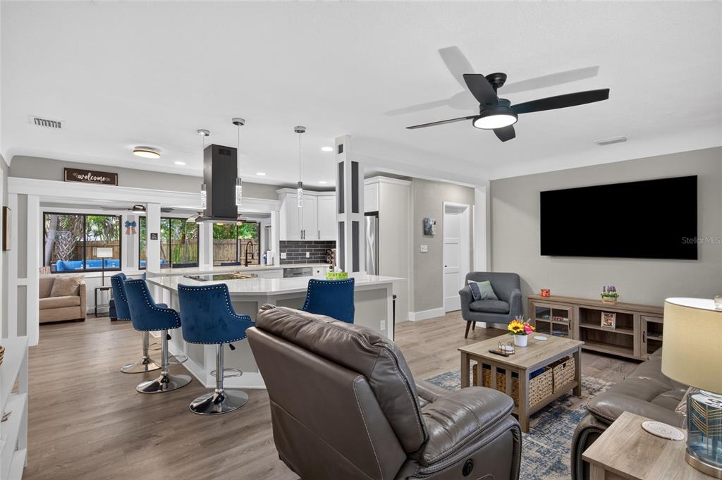 An open-concept living room and kitchen featuring a large island, blue barstools, and wood flooring — 2901 70TH STREET N, ST PETERSBURG, FL