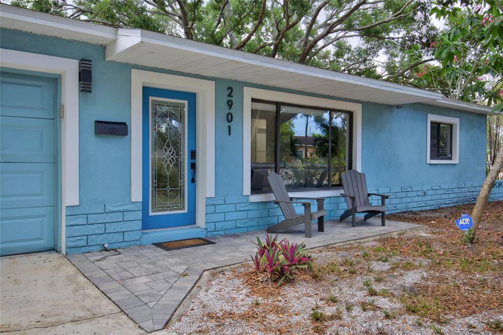 A blue house exterior features a front door, a large window, and two patio chairs — 2901 70TH STREET N, ST PETERSBURG, FL