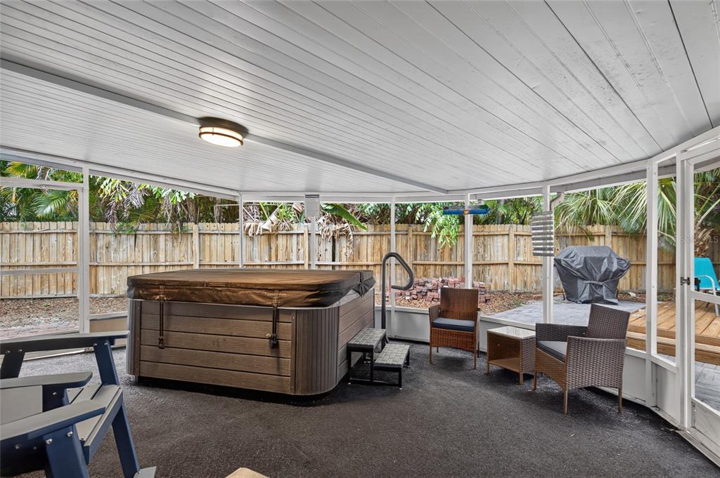 A screened-in patio features a hot tub, outdoor seating, and a view of the backyard — 2901 70TH STREET N, ST PETERSBURG, FL