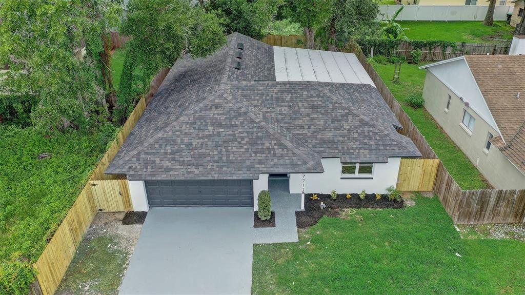An aerial view of a single-story house with a gray shingled roof and garage — 7711 LAKESIDE WOODS DRIVE, ORLANDO, FL