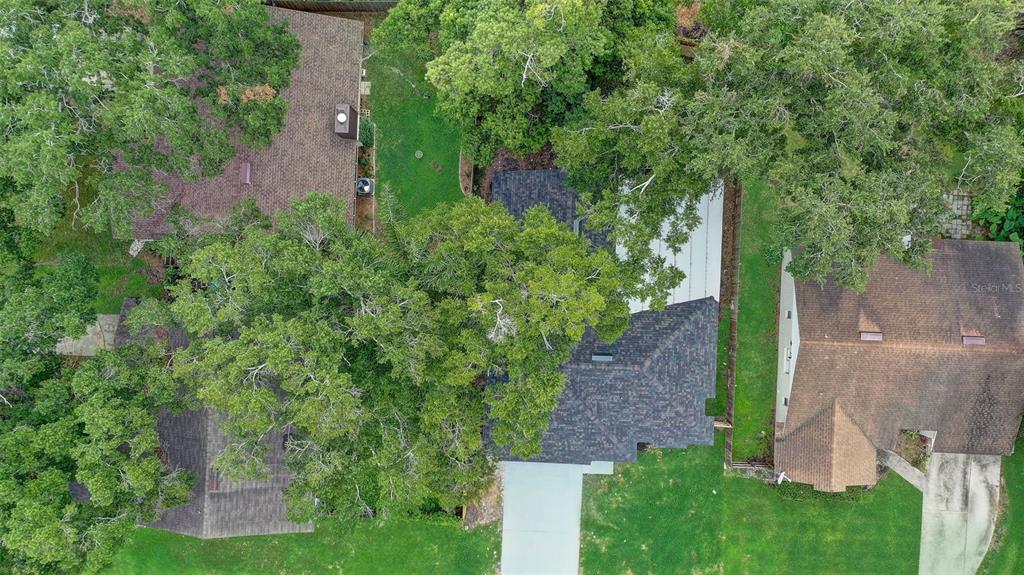 An aerial view shows three houses surrounded by mature trees and green lawns — 7711 LAKESIDE WOODS DRIVE, ORLANDO, FL