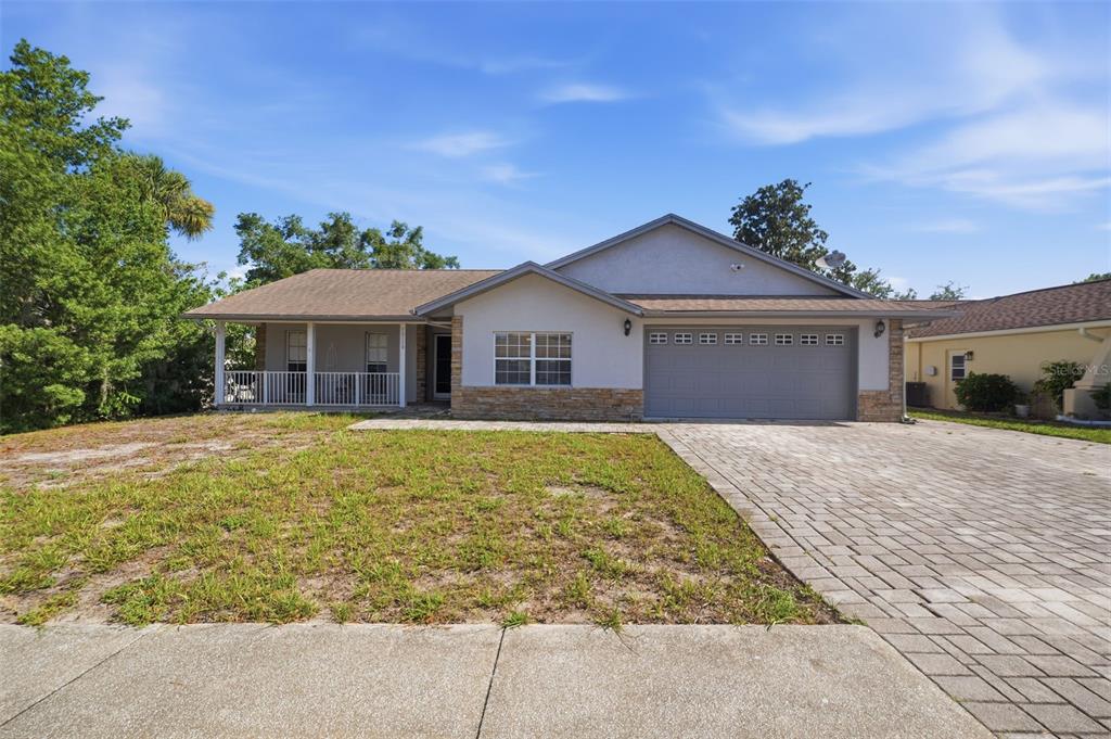 A single-story house with a stone facade, a two-car garage, and a front porch — 10110 BRIAR CIRCLE, HUDSON, FL