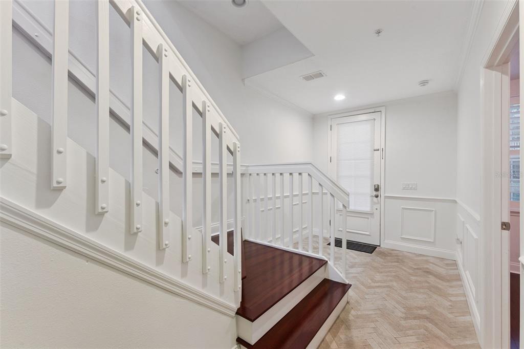 A staircase with dark wood treads and white railings leads to a landing with a door — 1650 PROSPECT AVENUE, ORLANDO, FL