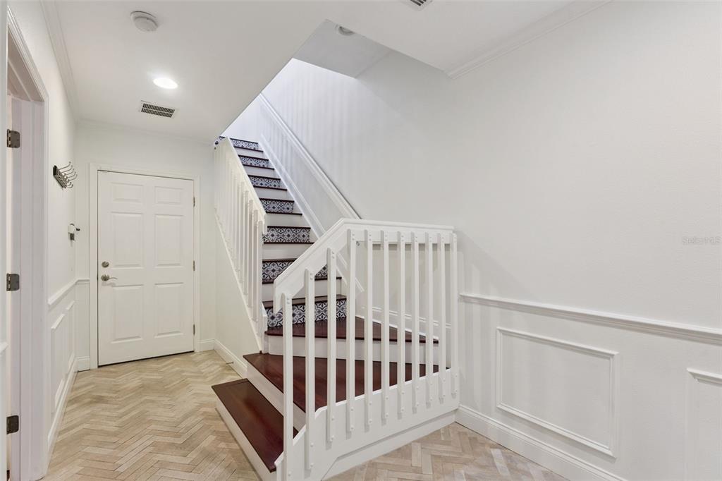 An entryway features a staircase with patterned risers, dark wood treads, and white railings — 1650 PROSPECT AVENUE, ORLANDO, FL