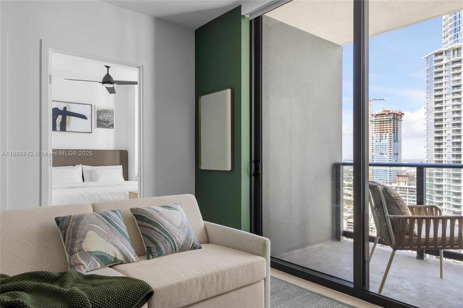 A living room with a beige sofa faces a balcony overlooking a city skyline — 159 NE 6TH ST # 3013, Miami FL 33132, MIAMI, FL