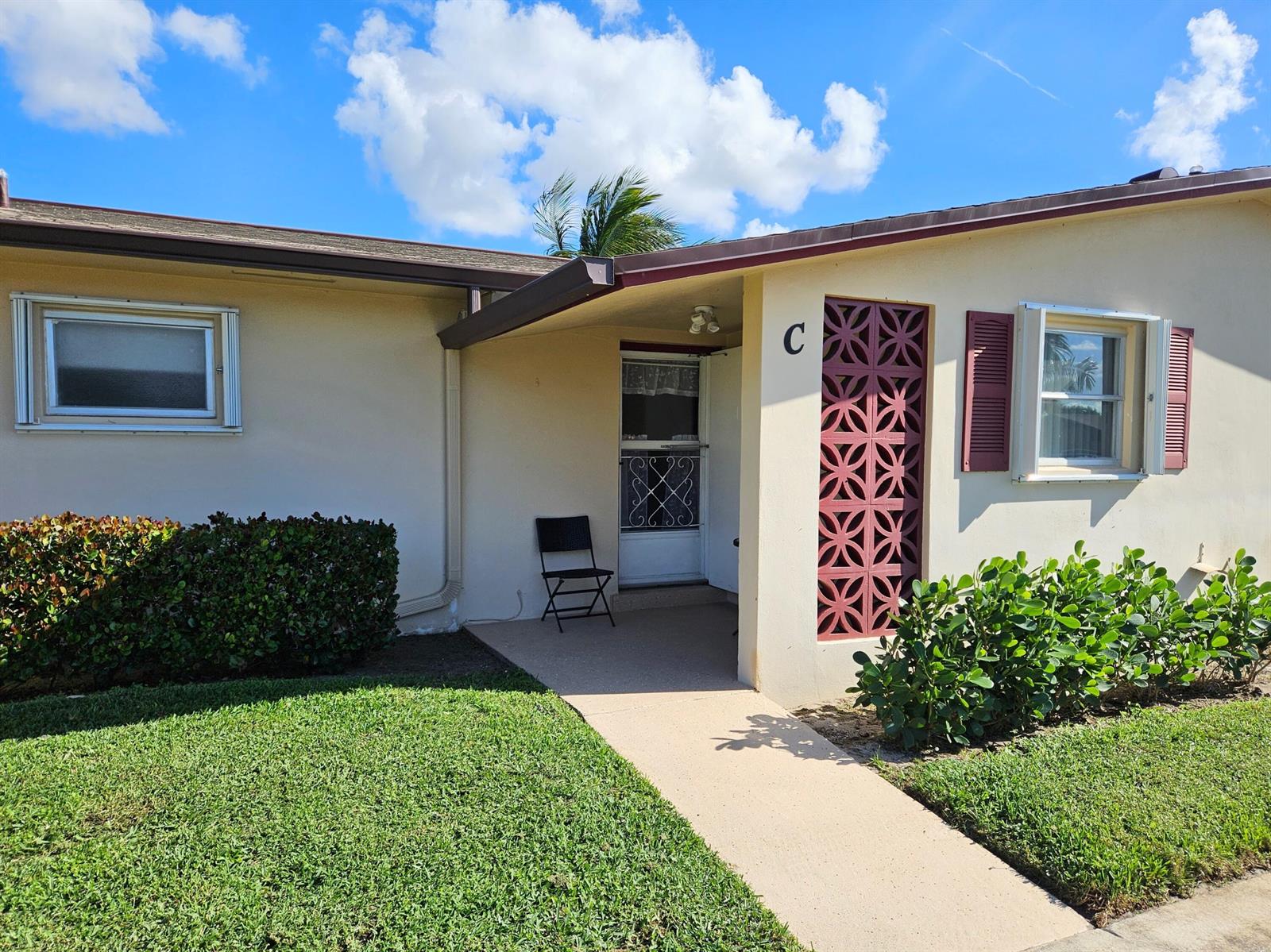 The exterior of a single-story unit features a concrete walkway, a decorative screen, and landscaping — 2950 Crosley Drive E # C, West Palm Beach FL 33415, WEST PALM BEACH, FL