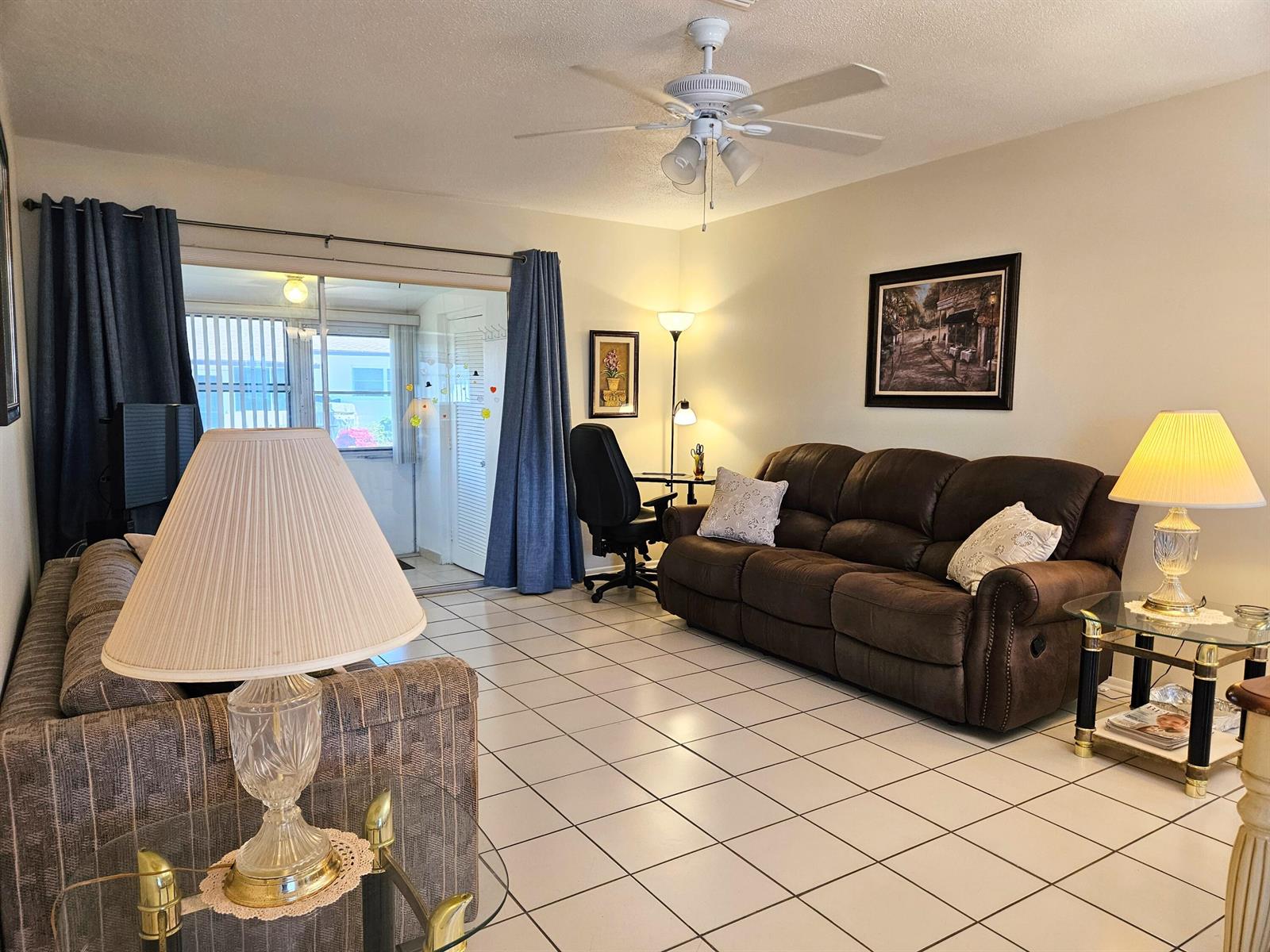 A living room features tiled floors, a brown sofa, a ceiling fan, and sliding glass doors — 2950 Crosley Drive E # C, West Palm Beach FL 33415, WEST PALM BEACH, FL