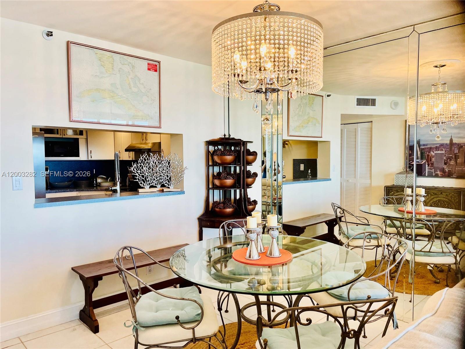 A dining area features a glass-topped table, metal chairs, and a large crystal chandelier — 2555 Collins Ave # 1805, Miami Beach FL 33140, MIAMI BEACH, FL