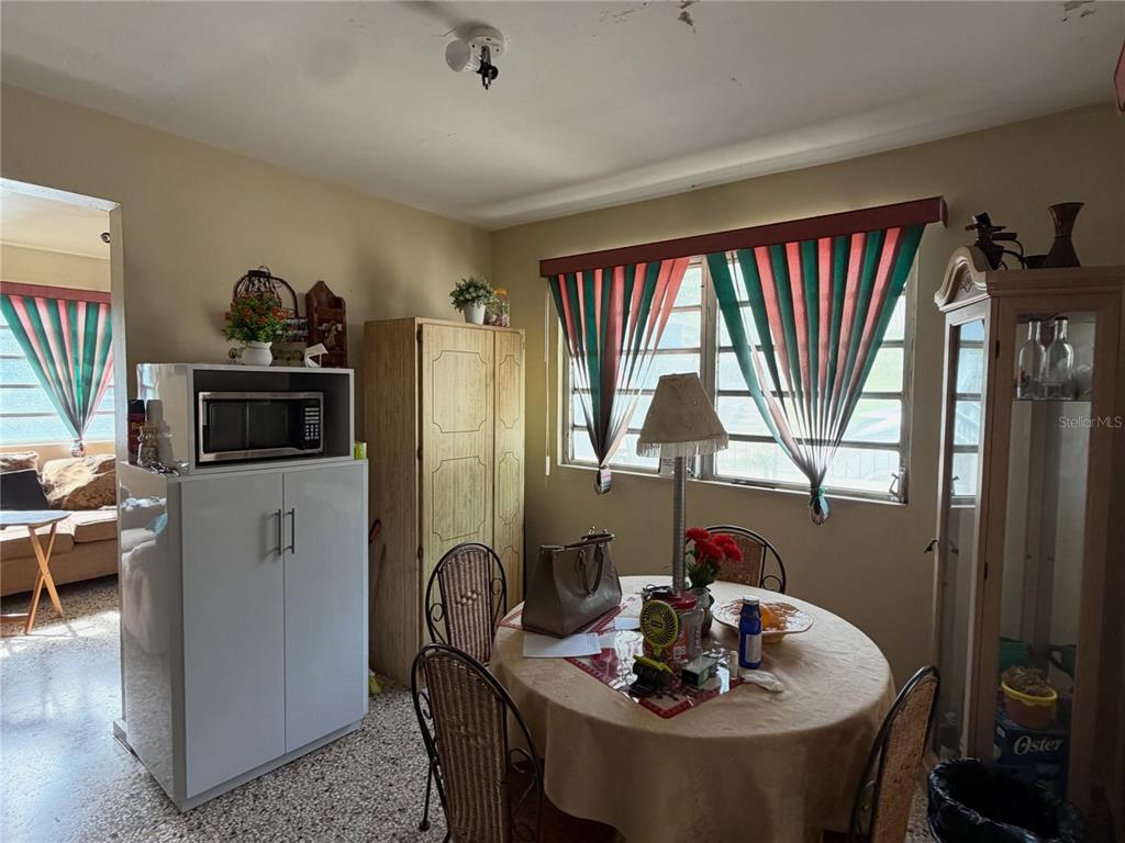 A dining area features a round table, chairs, a microwave cabinet, and a tall display case — 156 Km 0.7 PUEBLO, OROCOVIS, PR