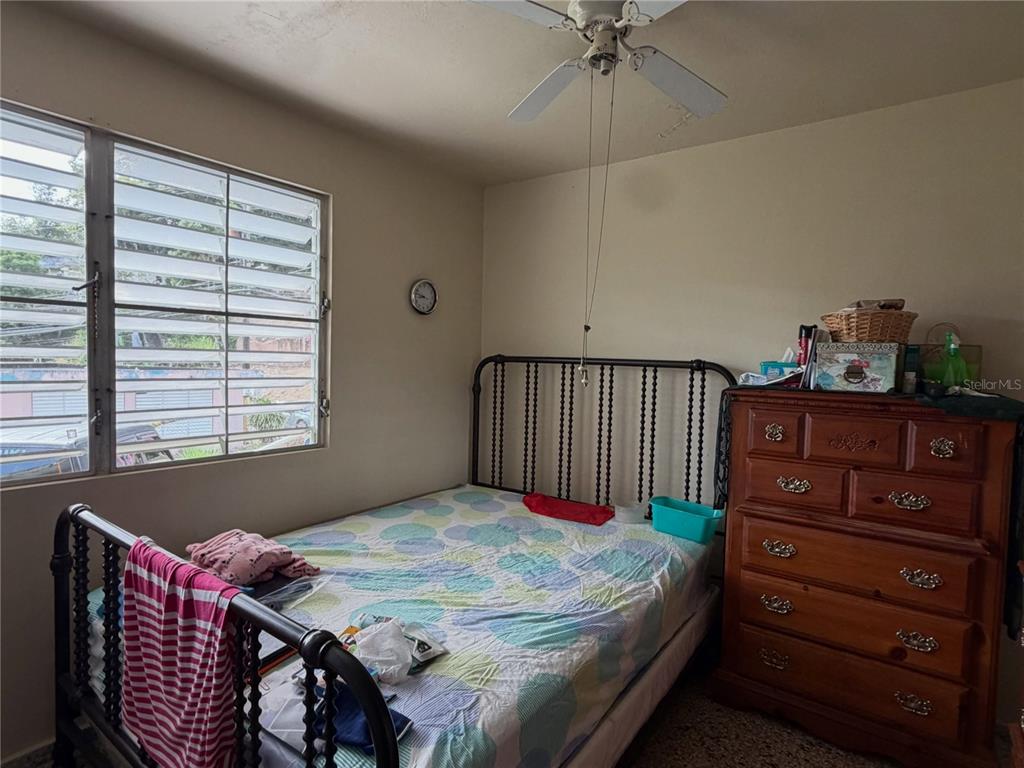 A bedroom features a metal bed frame, a wooden dresser, and a louvered window — 156 Km 0.7 PUEBLO, OROCOVIS, PR