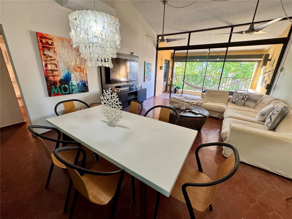 A dining area with a white table and chairs sits before a living room with a balcony — 100 CANDELERO DRIVE UNIT 2067, HUMACAO, PR