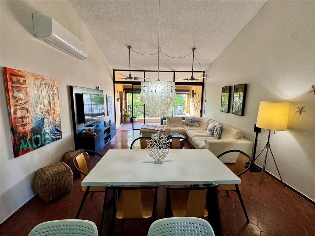 A dining area with a white table leads into a living room with a sectional sofa — 100 CANDELERO DRIVE UNIT 2067, HUMACAO, PR