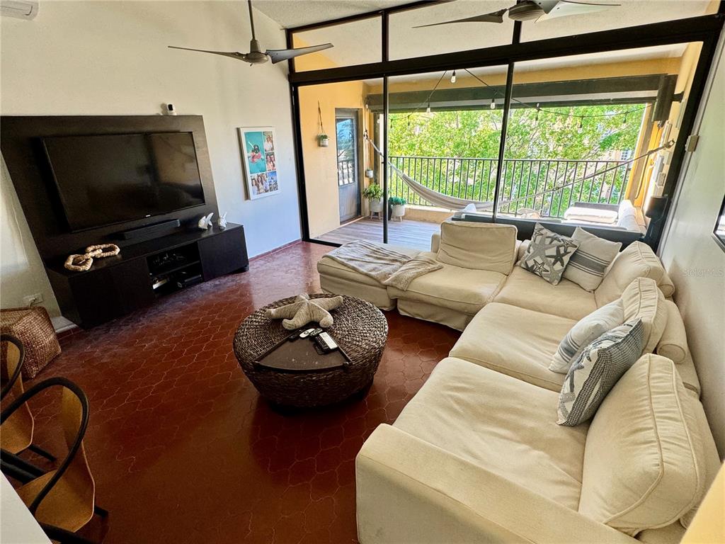 A living room features a white sectional sofa, a round woven coffee table, and a balcony — 100 CANDELERO DRIVE UNIT 2067, HUMACAO, PR