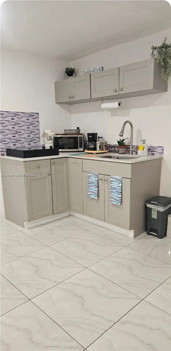 A small kitchen features light gray cabinets, white countertops, and a tiled backsplash — 144 NW 7th Ave # 1, Dania Beach FL 33004, DANIA BEACH, FL