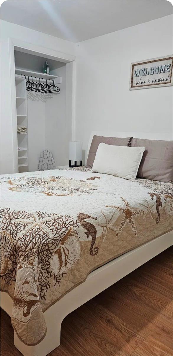 A bedroom features a bed with a coastal-themed quilt, a white headboard, and a closet — 144 NW 7th Ave # 1, Dania Beach FL 33004, DANIA BEACH, FL