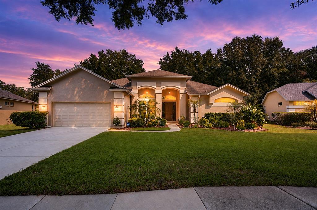 A single-story suburban house with a two-car garage and a landscaped front yard at sunset — 4916 WILLOW RIDGE TERRACE, VALRICO, FL