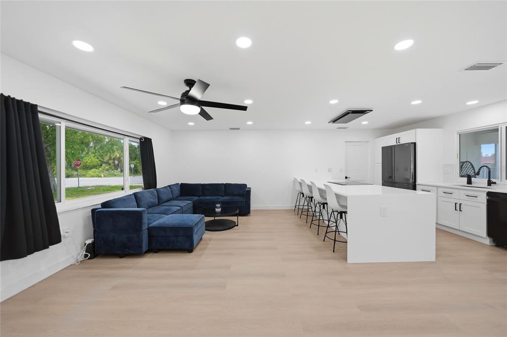 A modern open-concept living room and kitchen featuring a blue sectional, white island, and light flooring — 2506 LAKESHORE CIRCLE, PORT CHARLOTTE, FL