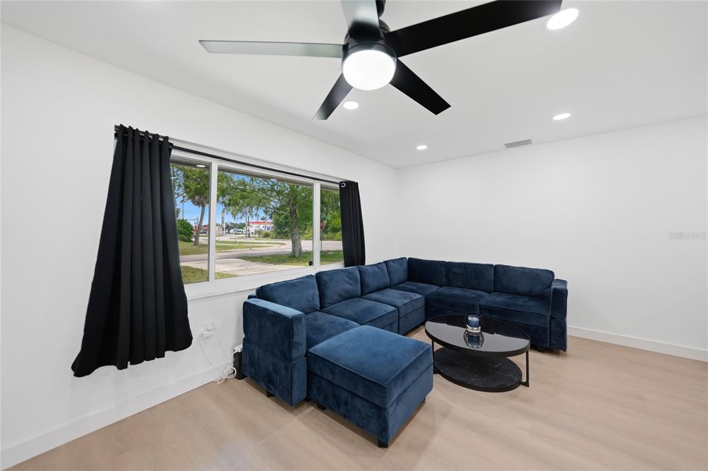 A living room features a blue sectional sofa, a black coffee table, and a ceiling fan — 2506 LAKESHORE CIRCLE, PORT CHARLOTTE, FL