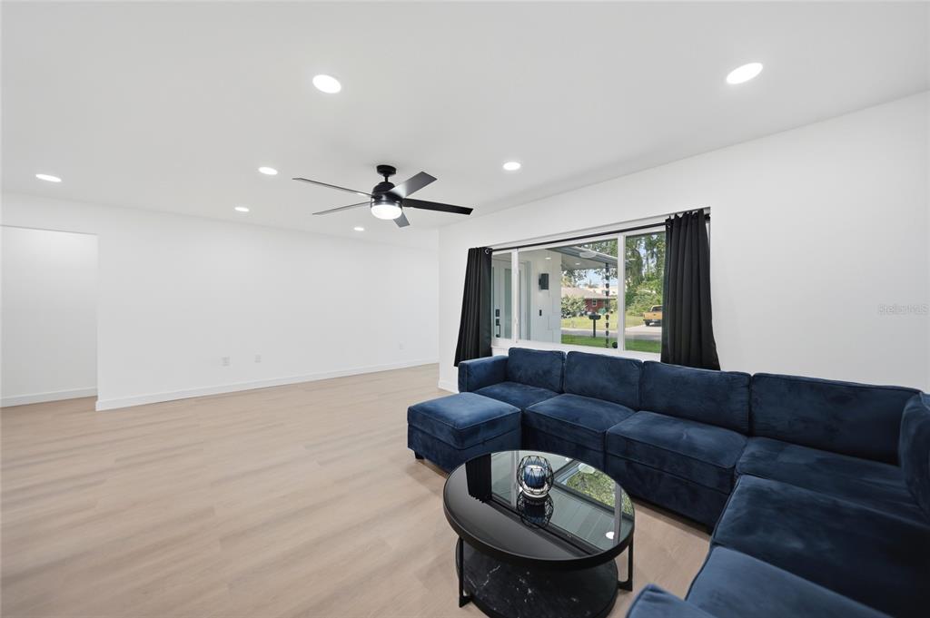 A living room features light wood flooring, a blue sectional sofa, and a black coffee table — 2506 LAKESHORE CIRCLE, PORT CHARLOTTE, FL