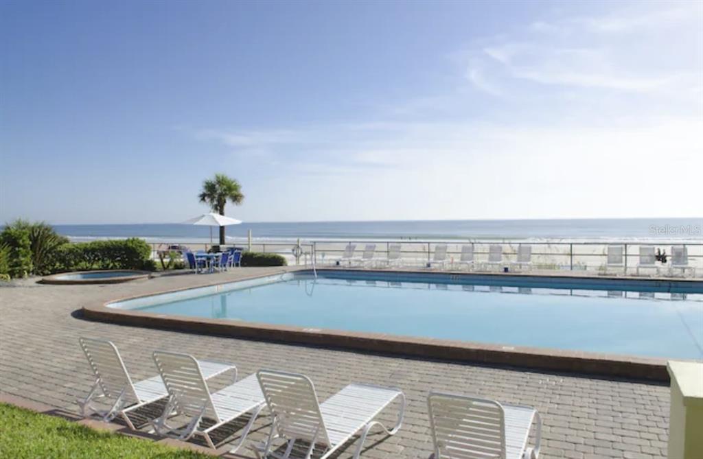 A rectangular swimming pool sits on a brick patio overlooking the ocean and beach — 1909 S ATLANTIC AVENUE UNIT 520 & 521, DAYTONA BEACH, FL
