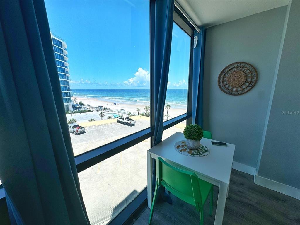A small dining table sits by a large window overlooking the beach and ocean — 1909 S ATLANTIC AVENUE UNIT 520 & 521, DAYTONA BEACH, FL