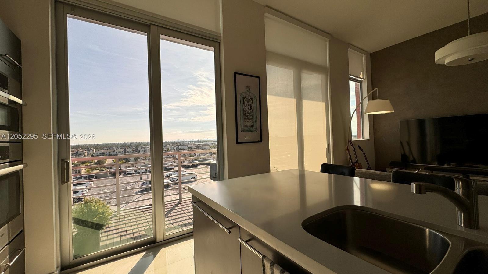 A modern kitchen with a stainless steel sink overlooks a balcony and suburban landscape — 7875 NW 107th Ave # 812, Doral FL 33178, DORAL, FL