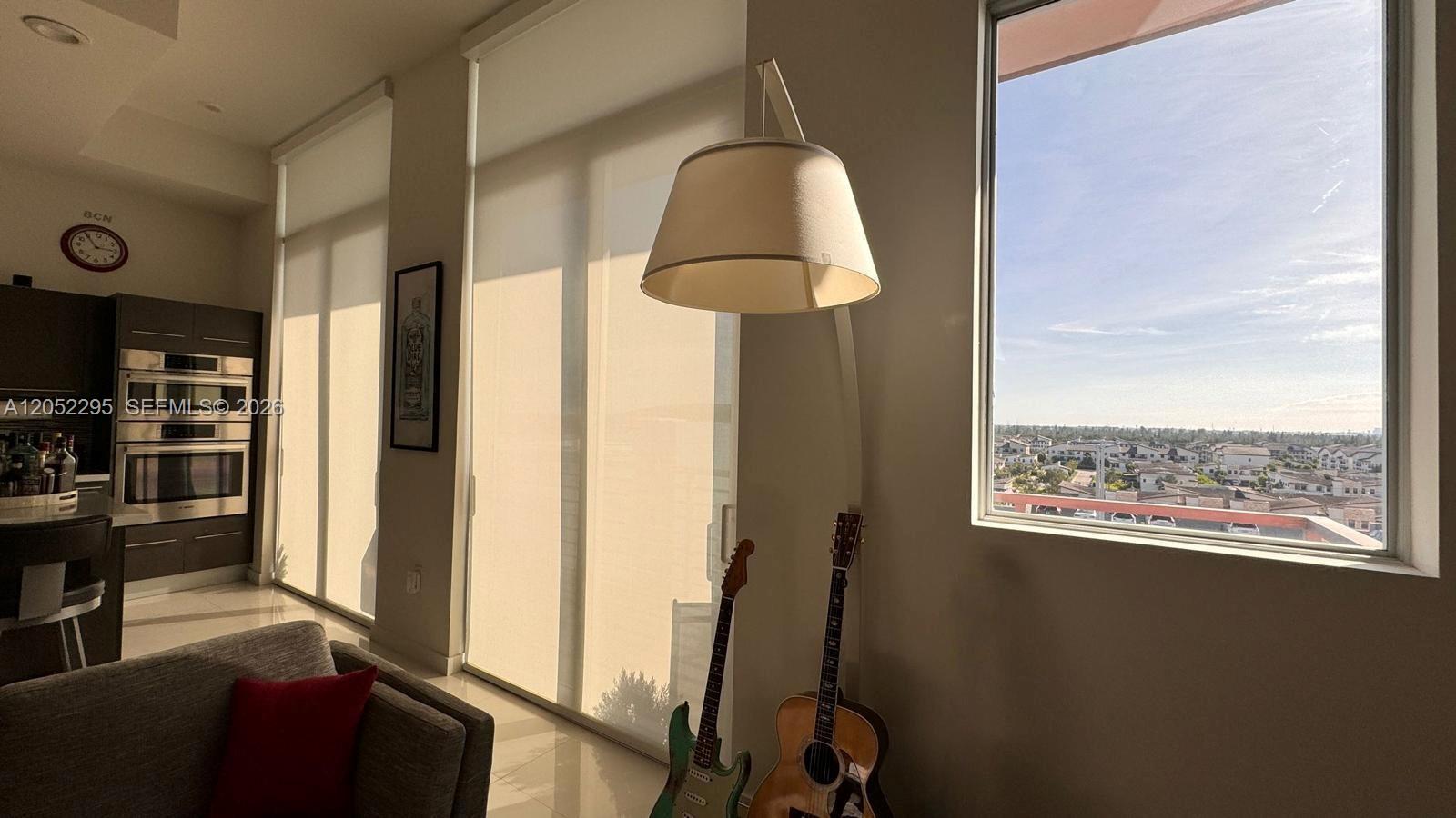 A living room features a large window, a pendant lamp, and two guitars — 7875 NW 107th Ave # 812, Doral FL 33178, DORAL, FL