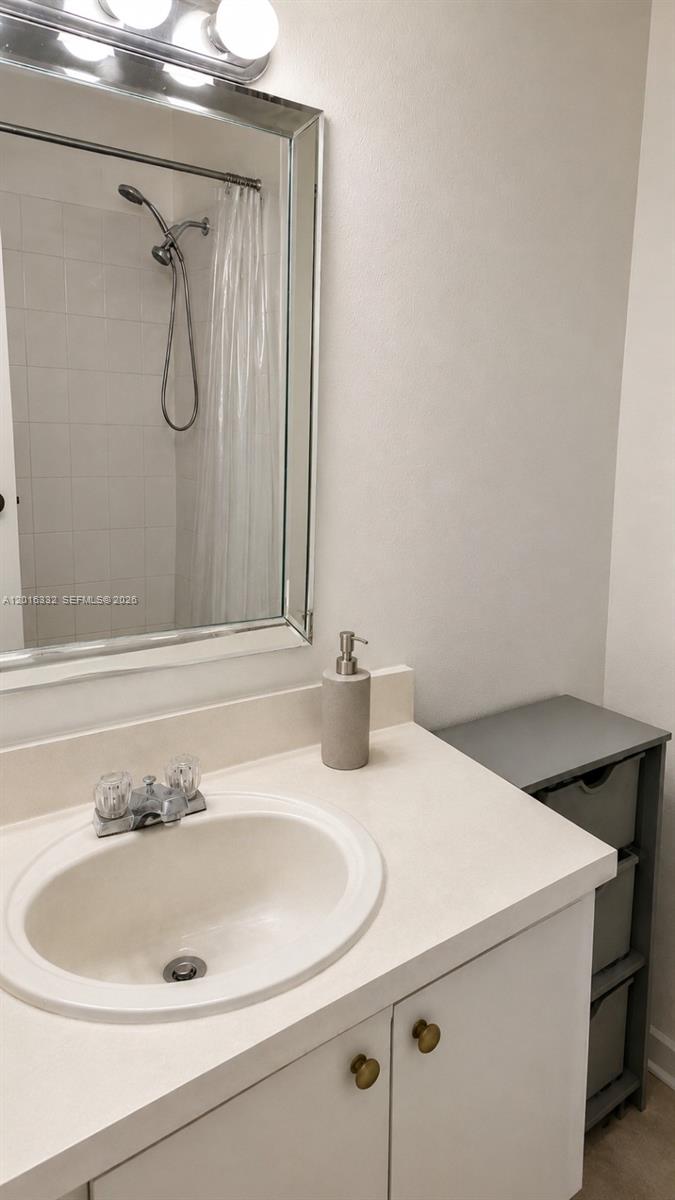 A bathroom features a white vanity with a sink, a mirror, and a shower stall — 17911 NW 68th Ave # M201, Hialeah FL 33015, HIALEAH, FL
