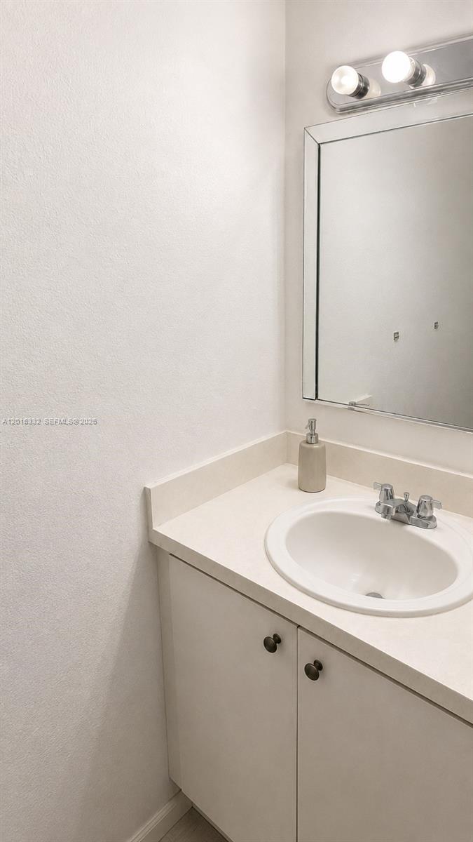 A bathroom features a white vanity with a sink, a mirror, and wall lighting — 17911 NW 68th Ave # M201, Hialeah FL 33015, HIALEAH, FL