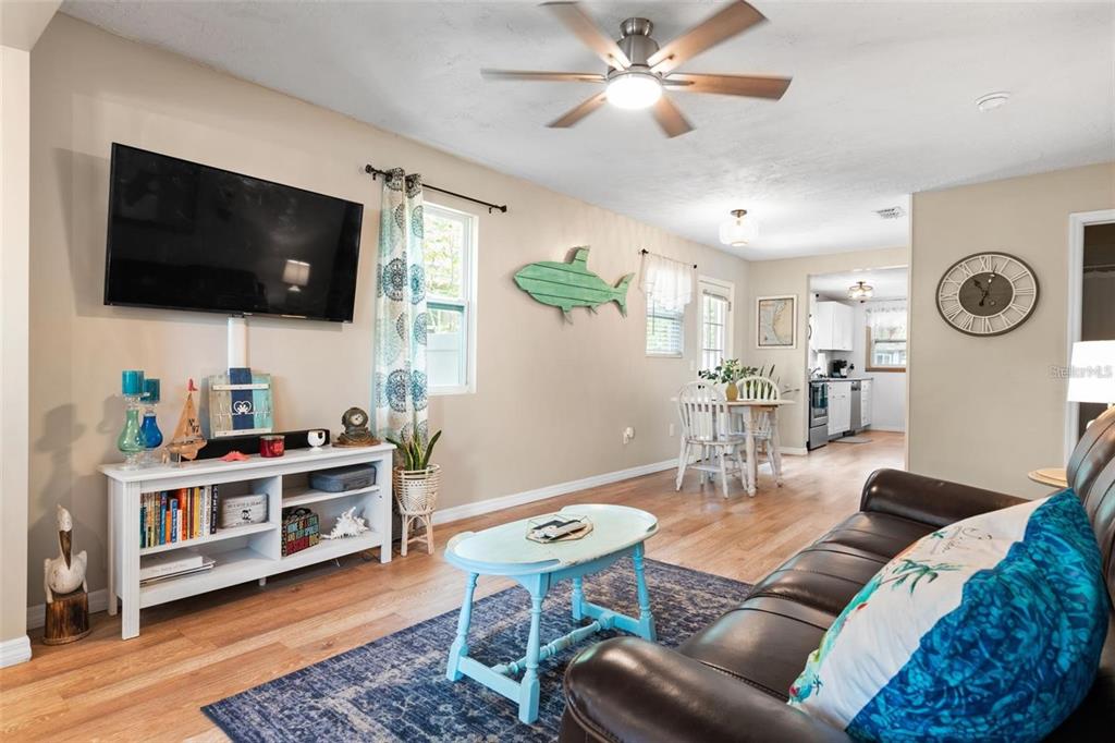 A living room with a television, white media console, coffee table, and adjacent dining area — 508 5TH AVENUE NE, LARGO, FL