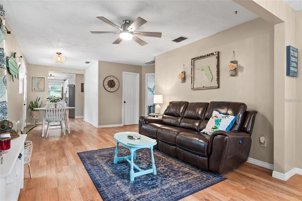 A living room features a brown leather sofa, a blue coffee table, and wood flooring — 508 5TH AVENUE NE, LARGO, FL