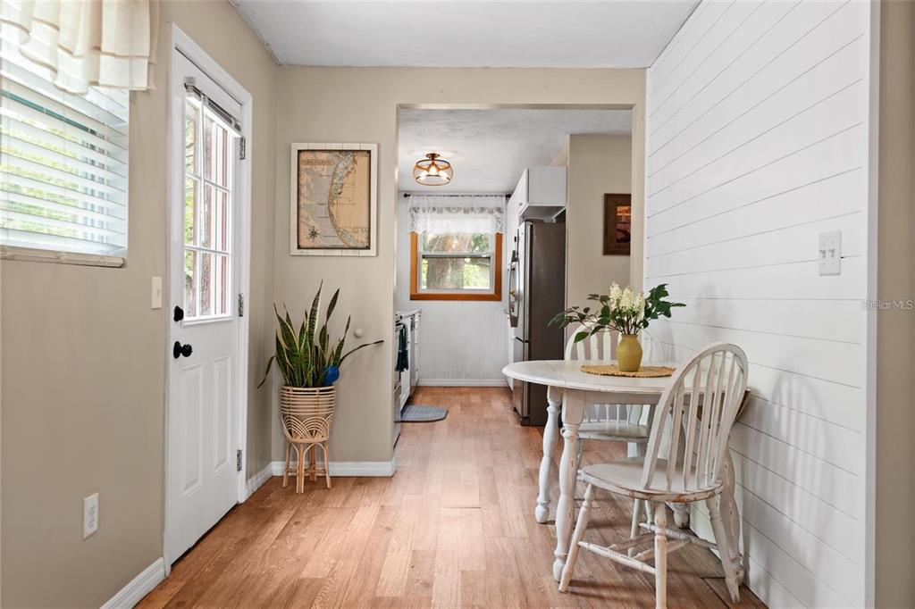 A dining area with wood floors, shiplap walls, and a view into the kitchen — 508 5TH AVENUE NE, LARGO, FL