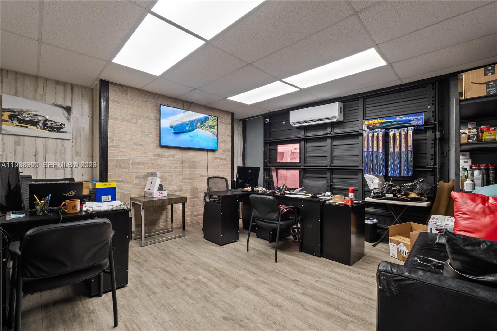 An office space features a brick accent wall, black desks, and a wall-mounted television — 4350 NW 32nd Ave, Miami FL 33142, MIAMI, FL