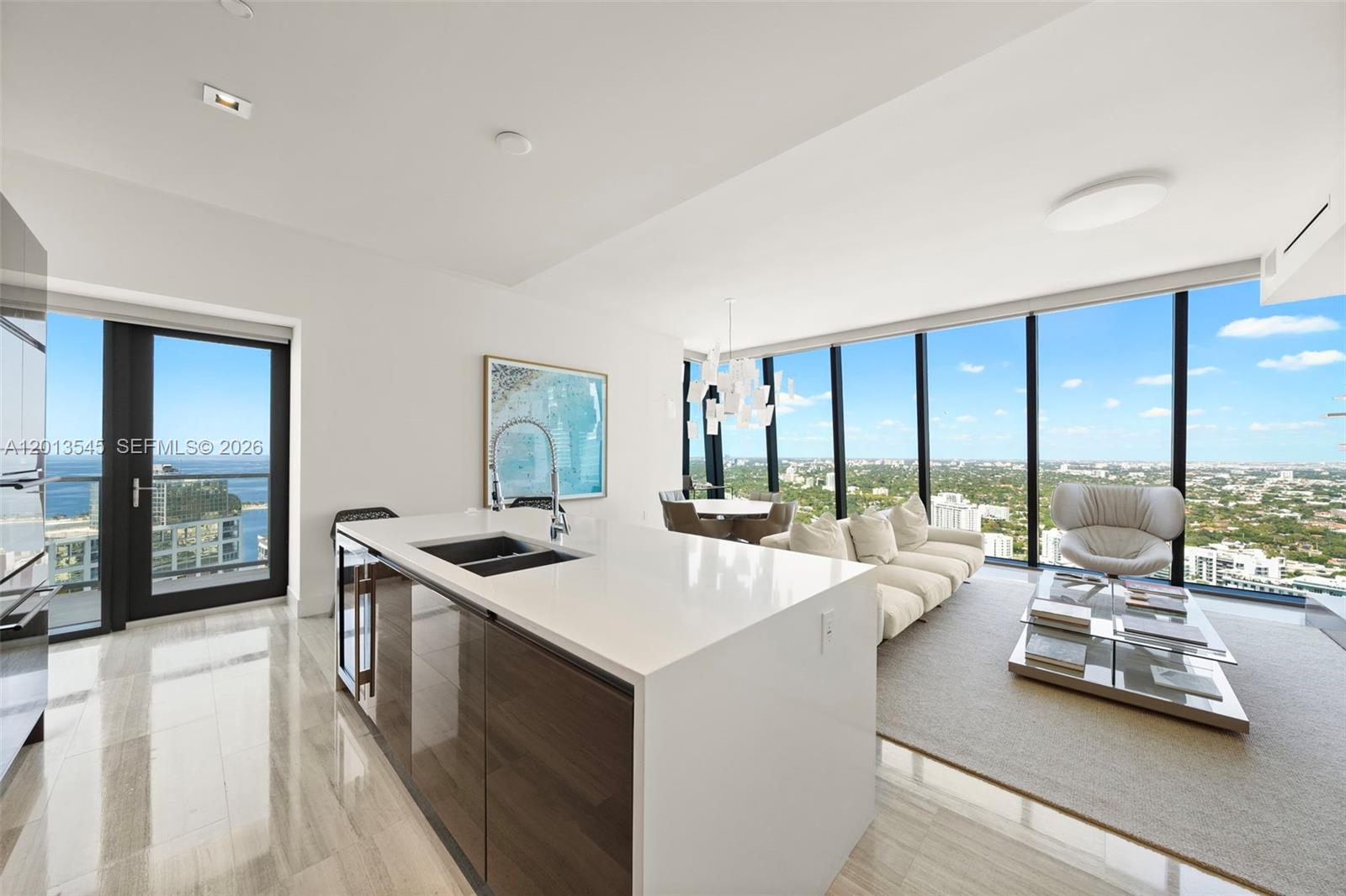 A modern kitchen island with a sink overlooks a living area with floor-to-ceiling windows — 1451 Brickell Ave # 4103, Miami FL 33131, MIAMI, FL