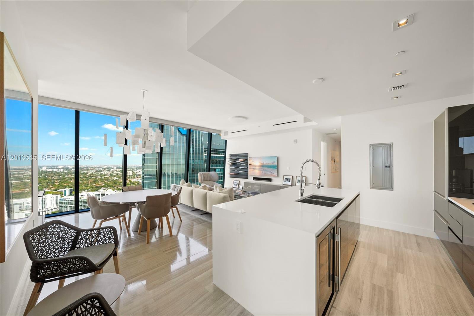 A modern open-concept living and dining area features floor-to-ceiling windows and a white kitchen island — 1451 Brickell Ave # 4103, Miami FL 33131, MIAMI, FL