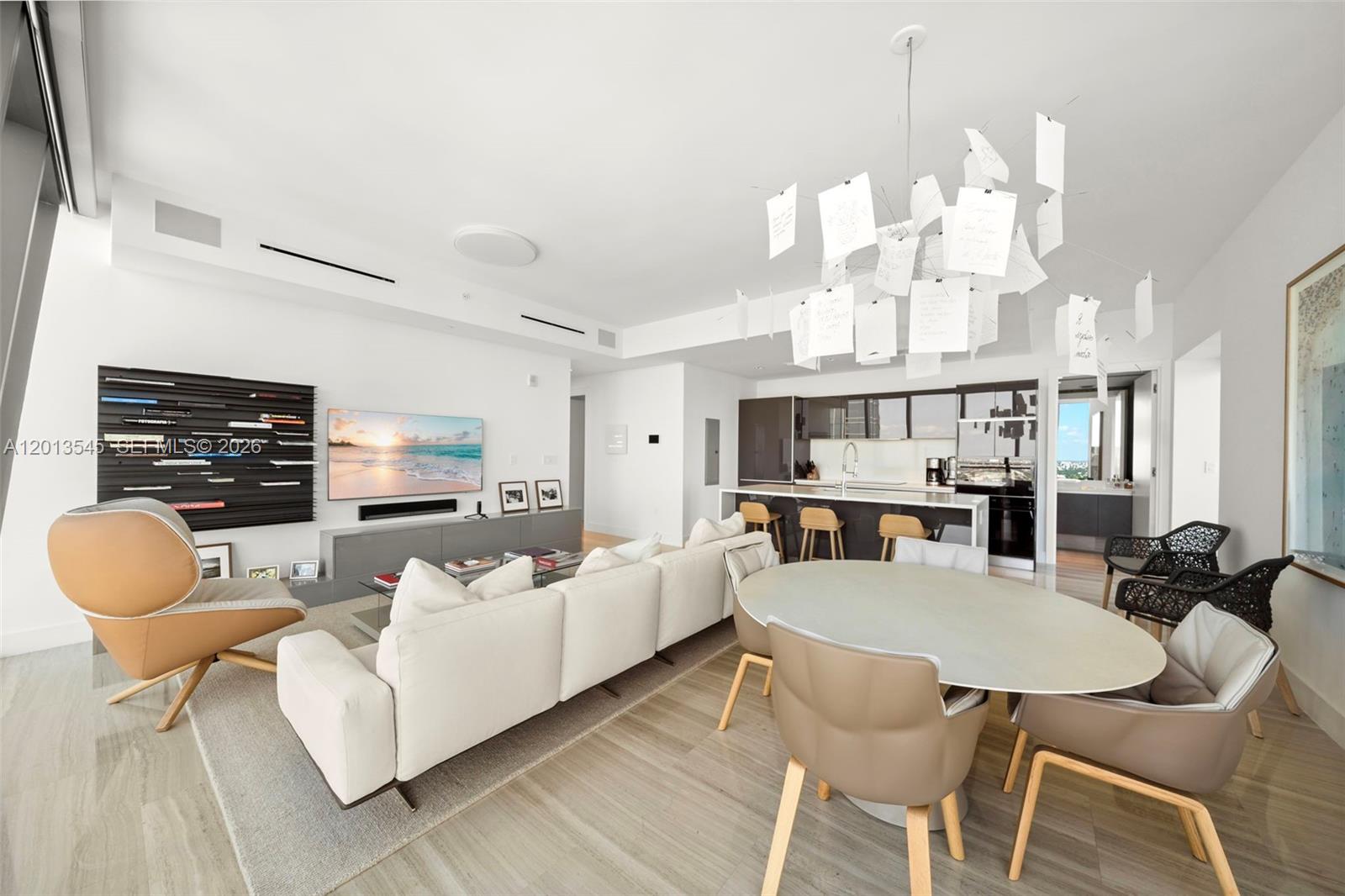 A modern open-concept living and dining area features a white sofa, round table, and chandelier — 1451 Brickell Ave # 4103, Miami FL 33131, MIAMI, FL