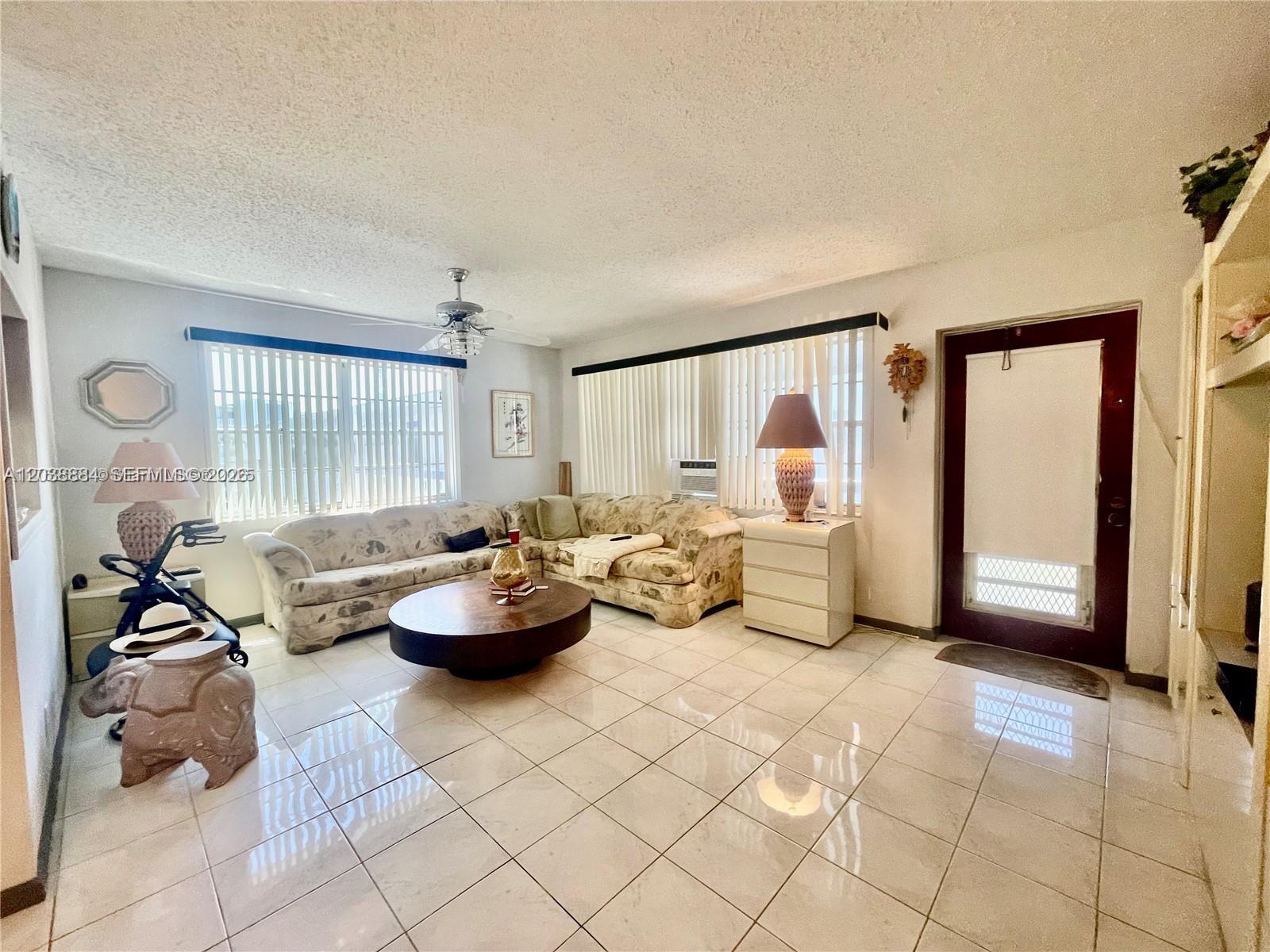 A living room features a sectional sofa, a round coffee table, and light-colored tile flooring — 337 Durham J # 337, Deerfield Beach FL 33442, DEERFIELD BEACH, FL