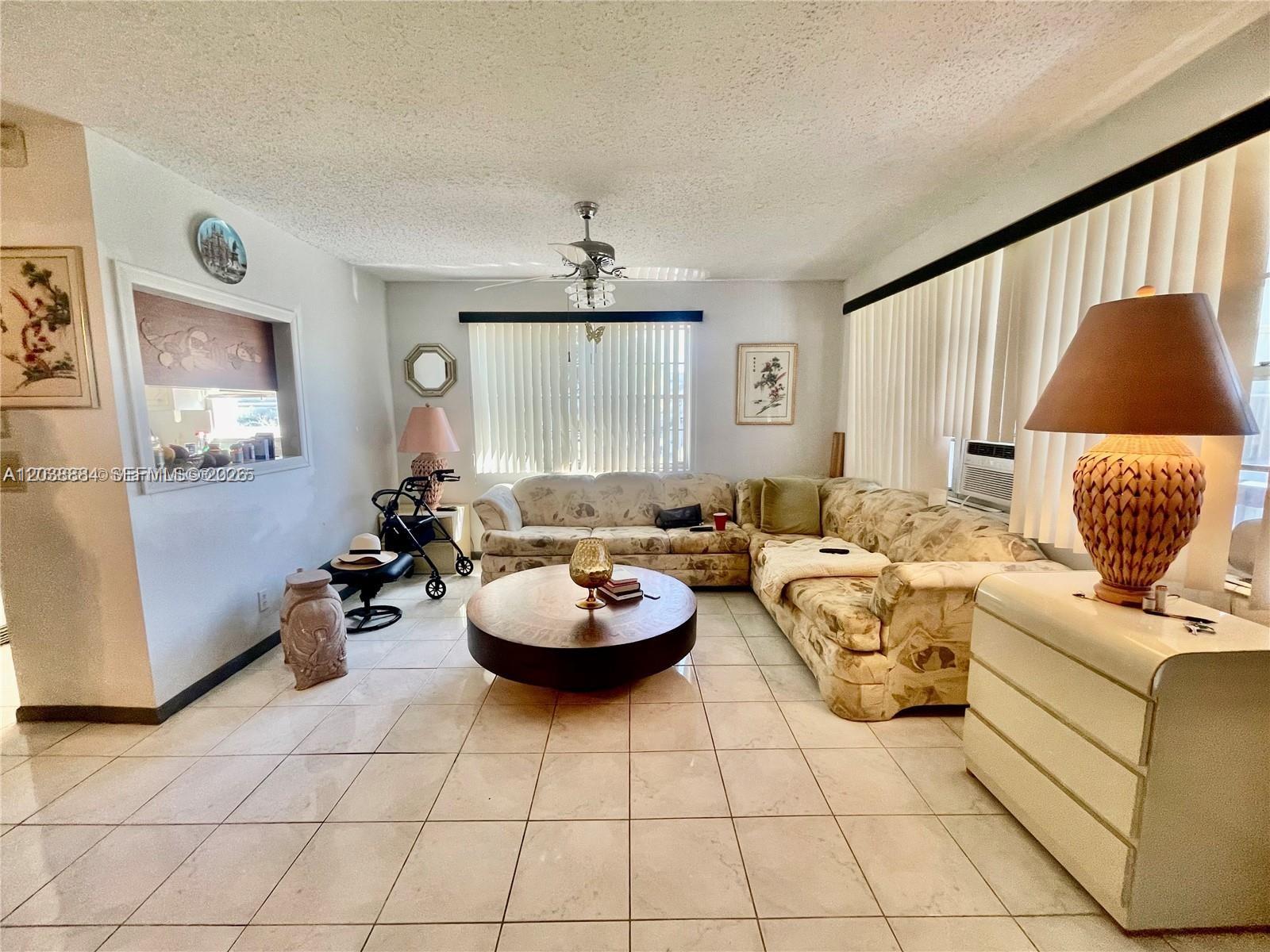 A living room features a large sectional sofa, a round coffee table, and tile flooring — 337 Durham J # 337, Deerfield Beach FL 33442, DEERFIELD BEACH, FL