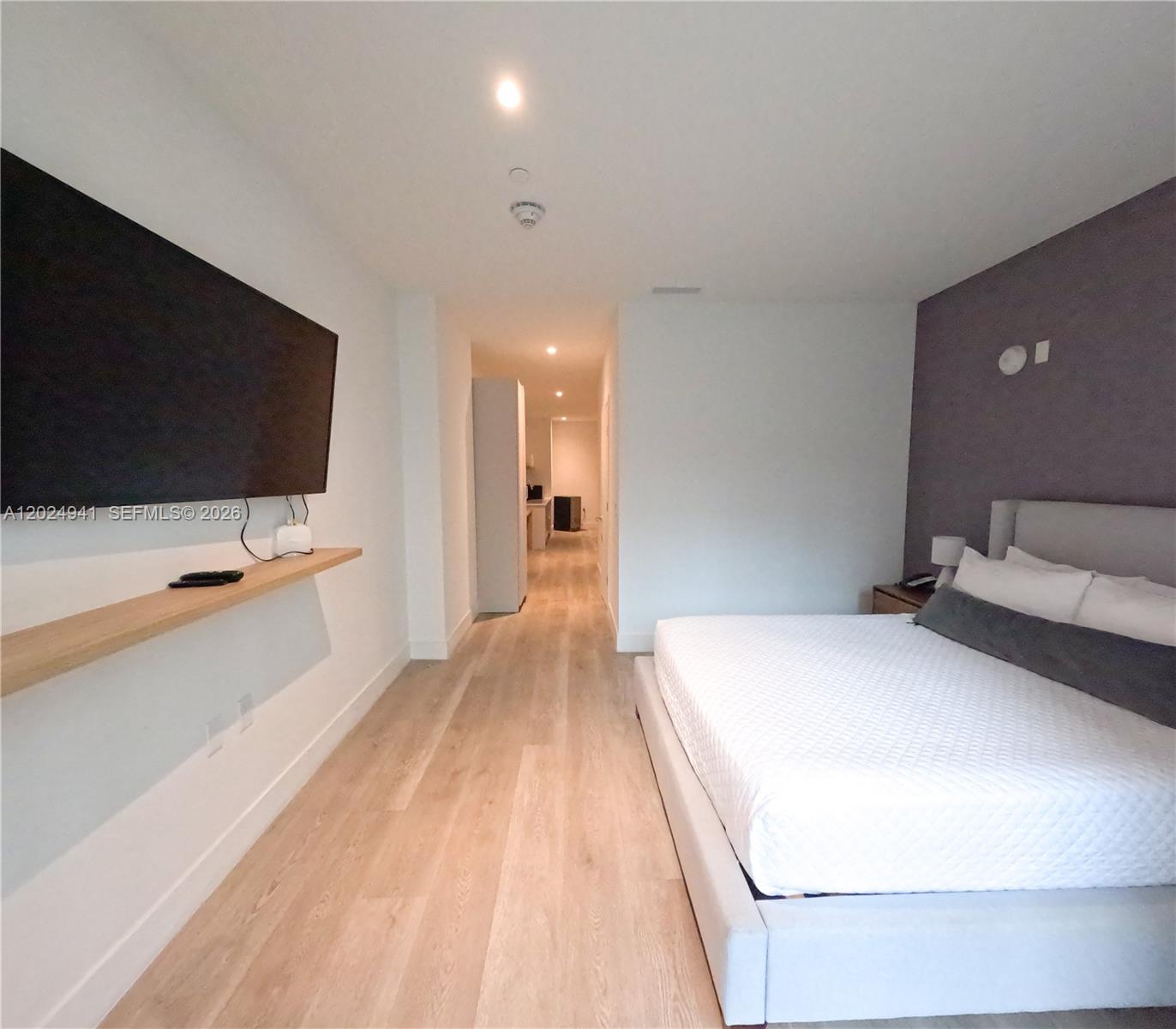 A bedroom features a wall-mounted television, a floating shelf, and a bed against a purple wall — 229 SW 9th St # 508, Miami FL 33130, MIAMI, FL