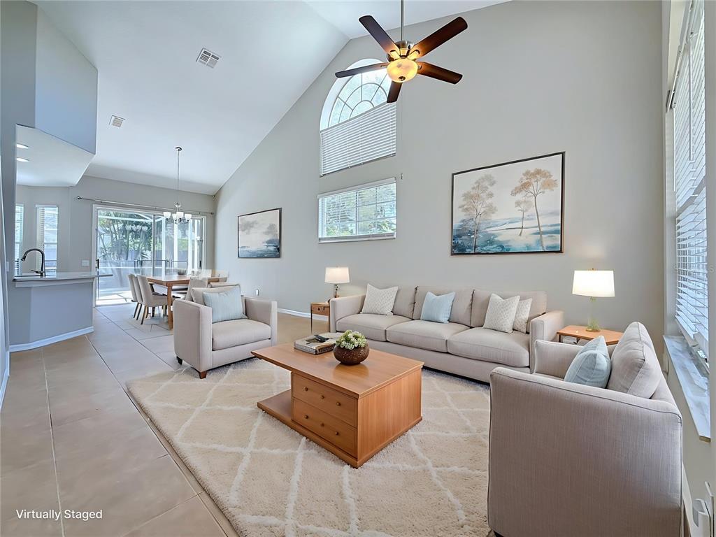 A living room with vaulted ceilings, a ceiling fan, and neutral furniture on a rug — 437 BRILAND STREET, TARPON SPRINGS, FL