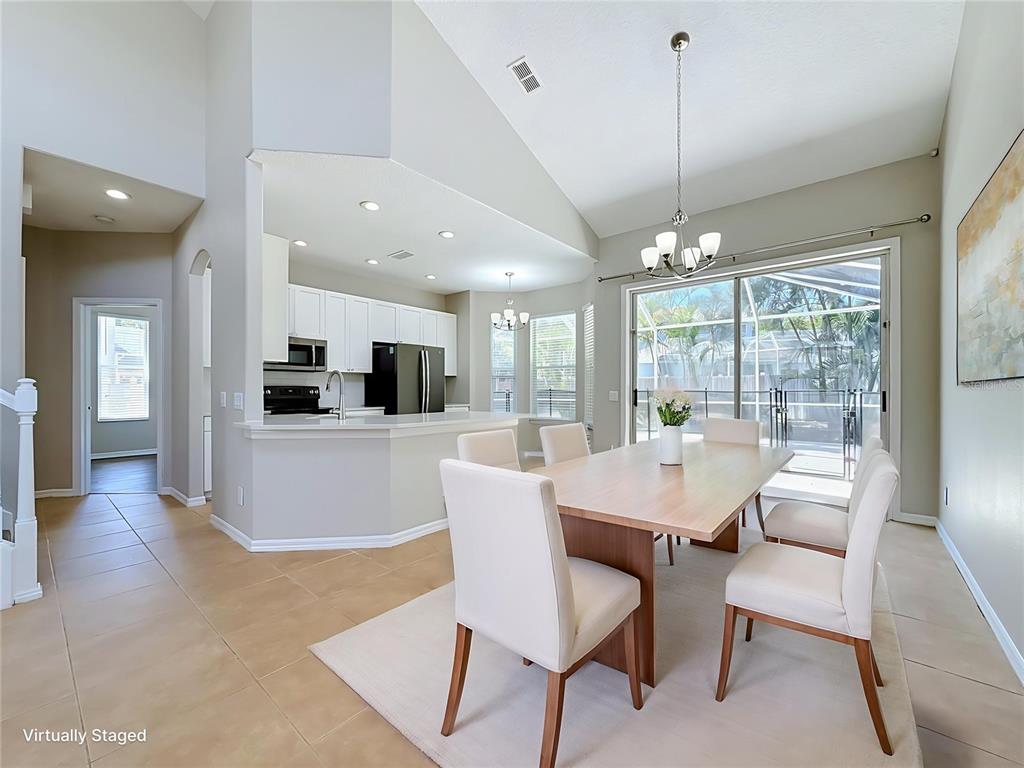 A dining area with a wooden table and chairs sits adjacent to a white kitchen — 437 BRILAND STREET, TARPON SPRINGS, FL