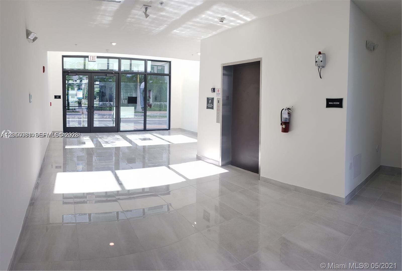 A modern building lobby features tiled floors, an elevator, and glass entrance doors — 8363 NW 41st St # 104, Doral FL 33166, DORAL, FL
