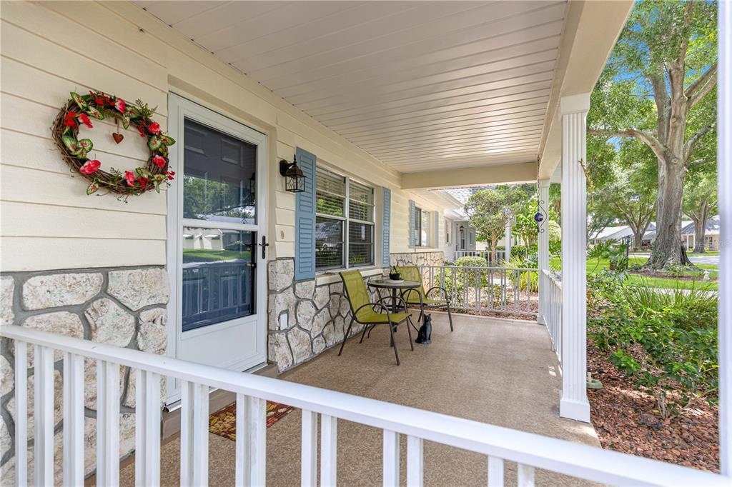 A covered front porch features stone siding, a white railing, and a small bistro set — 8841 SW 91ST STREET UNIT D, OCALA, FL