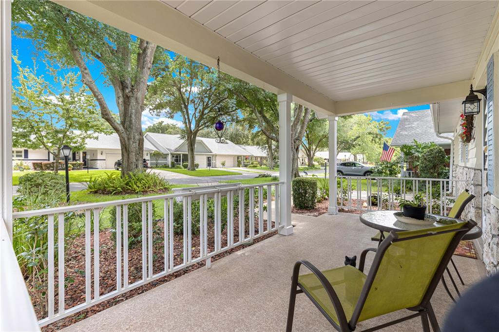 A covered front porch with a white railing, concrete floor, and outdoor seating — 8841 SW 91ST STREET UNIT D, OCALA, FL
