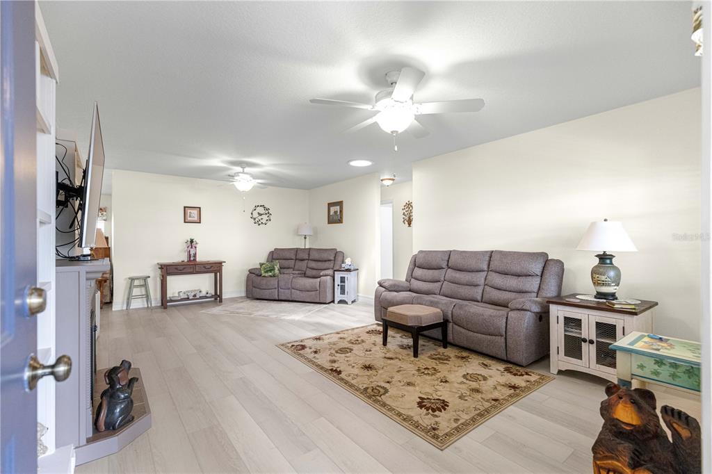 A living room features light wood flooring, two grey sofas, and two ceiling fans — 8841 SW 91ST STREET UNIT D, OCALA, FL