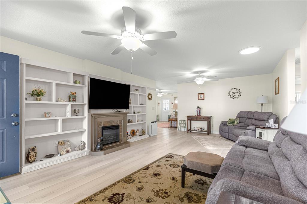 A living room features light wood flooring, a fireplace with built-in shelving, and two ceiling fans — 8841 SW 91ST STREET UNIT D, OCALA, FL