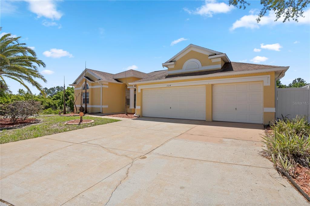 A yellow single-story house with a two-car garage and a concrete driveway — 334 GRAND RESERVE DRIVE, DAVENPORT, FL