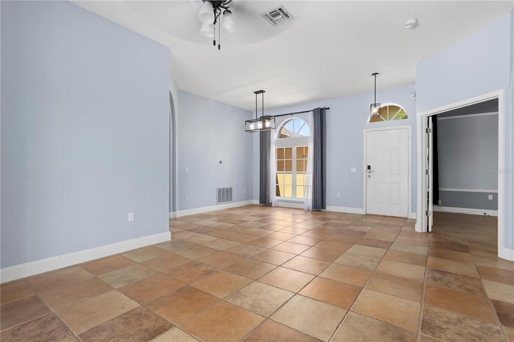 A tiled living room features an arched entryway to the kitchen and sliding glass doors — 334 GRAND RESERVE DRIVE, DAVENPORT, FL
